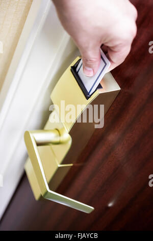 La main de personne déverrouillage d'une chambre d'hôtel porte par l'insertion d'une carte-clé dans une serrure électronique. Banque D'Images