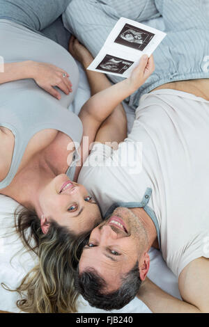 Expecting couple lying on bed Banque D'Images