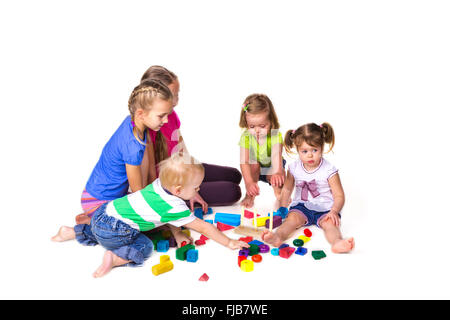 Heureux les enfants jouant avec des blocs de construction isolé sur blanc. Le travail d'équipe, la créativité concept. Banque D'Images