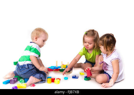 Heureux les enfants jouant avec des blocs de construction isolé sur blanc. Le travail d'équipe, la créativité concept. Banque D'Images