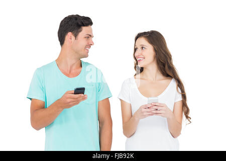Smiling couple en utilisant leurs smartphones Banque D'Images