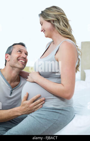 Expecting couple lying on bed and chatting Banque D'Images