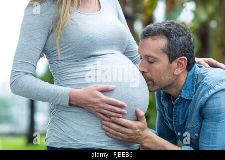 Man kissing pregnant womans estomac Banque D'Images