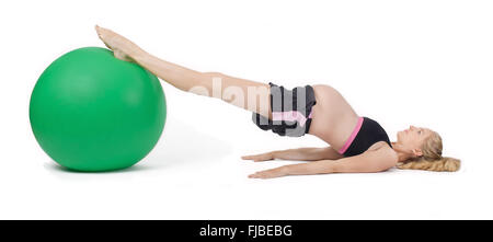 Femme enceinte en utilisant le yoga ball l'exécution de l'exercice lever la hanche. Banque D'Images