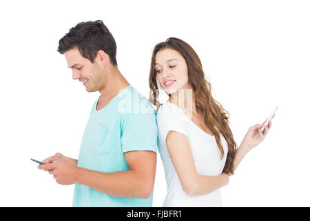 Smiling couple en utilisant leurs smartphones dos à dos Banque D'Images