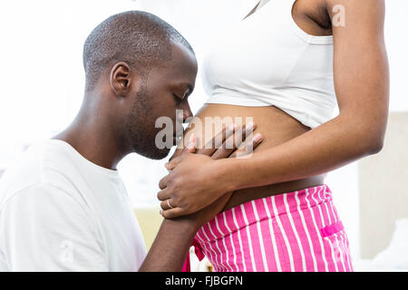 Man kissing pregnant womans belly dans la chambre Banque D'Images