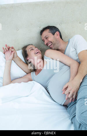 Expecting couple lying on bed and chatting Banque D'Images