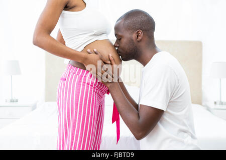 Man kissing pregnant womans belly dans la chambre Banque D'Images