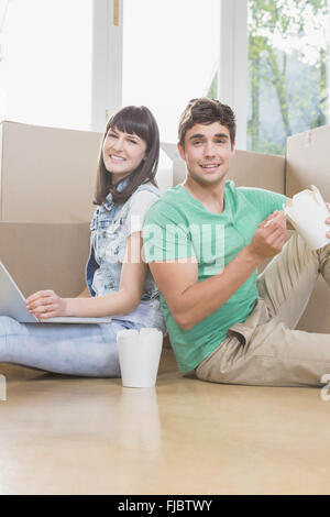 Jeune couple eating noodle and using laptop Banque D'Images