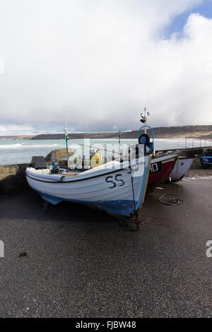 Les bateaux de pêche côtière halé par le port de Sennen Cove, Cornwall, UK sous un ciel d'hiver orageux Banque D'Images