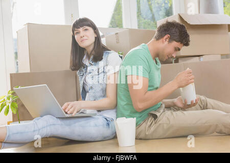 Jeune couple eating noodle and using laptop Banque D'Images