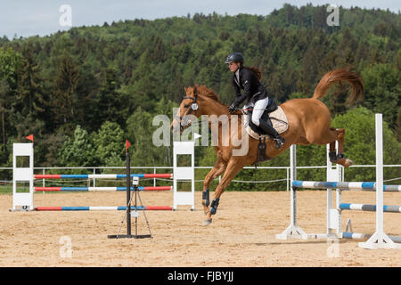 Vue latérale du jeune cavalière saute au-dessus de l'obstacle Banque D'Images