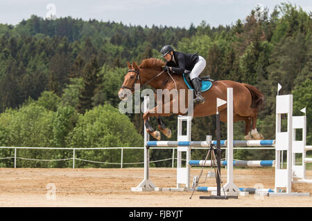 Vue de côté cavalière en noir veste qui saute Banque D'Images