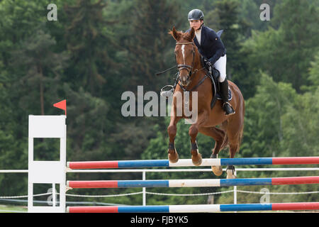 Vue latérale du jeune cavalière en noir veste qui saute par-dessus un obstacle Banque D'Images