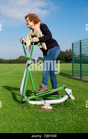 Femme exerçant sur la marche de la machine dans un parc public Banque D'Images