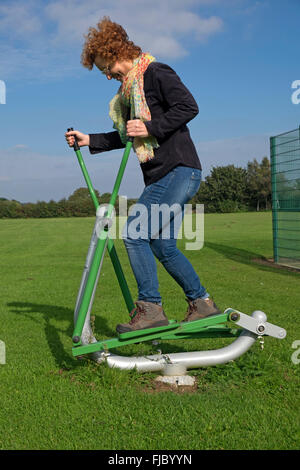 Femme exerçant sur la marche de la machine dans un parc public Banque D'Images