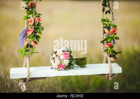 Mariage bouquet de pivoines couché sur banc swing blanche ornée de fleurs fraîches. Banque D'Images