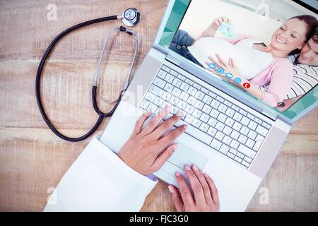 Composite image of happy pregnant woman holding baby shoes et de son mari sur un sof Banque D'Images