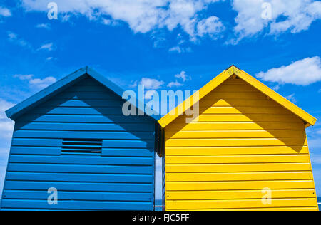 Deux couleurs bleu et jaune de cabanes de plage vu contre un ciel bleu profond, l'été, Whitby, North Yorkshire, England, UK Banque D'Images