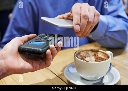 L'homme à l'aide de l'application de paiement sans contact sur téléphone mobile en Cafe Banque D'Images