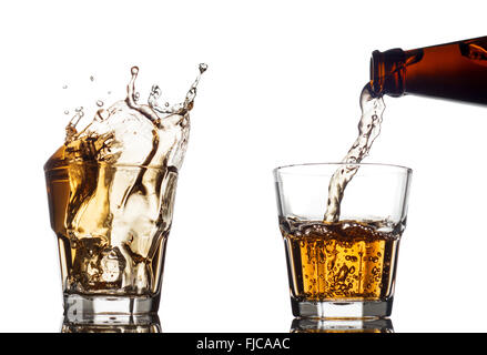 Verser le whisky dans un verre clair, sur fond blanc Banque D'Images