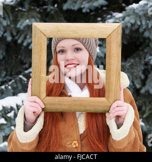 Woman outdoor portrait dans cadre photo en bois à l'hiver . Temps de neige dans la forêt de sapins. Banque D'Images