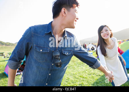 Jeune chinois couple holding hands on the grass Banque D'Images