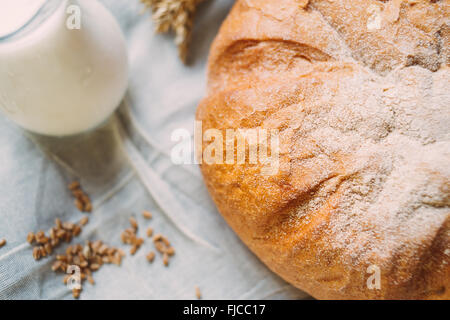 Verseuse en verre avec du lait et du pain sur les textiles blancs Banque D'Images