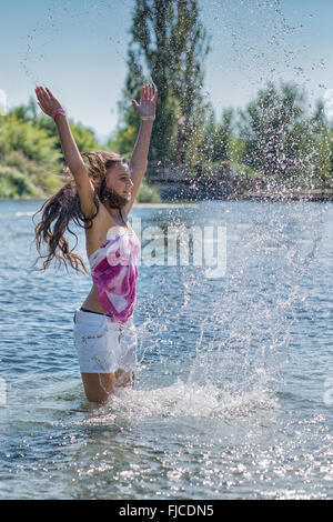 Girl with long hair jouer avec l'eau du lac Banque D'Images