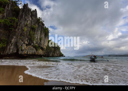 Outrigger Canoe amarré à la plage près de falaises sur la pendaison en Philippines Banque D'Images