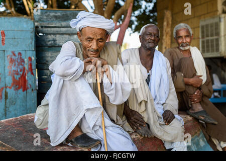 Portrait de trois vieux hommes musulmans reposant sur un bateau à l'envers sur les rives du Nil. Banque D'Images