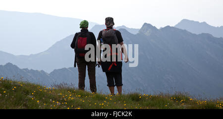 Les randonneurs de couple admiring view et prendre des photos de hautes montagnes Banque D'Images