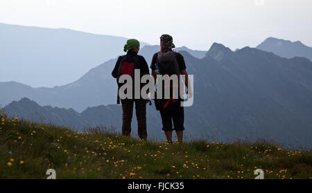 Les randonneurs de couple admiring view et prendre des photos de hautes montagnes Banque D'Images