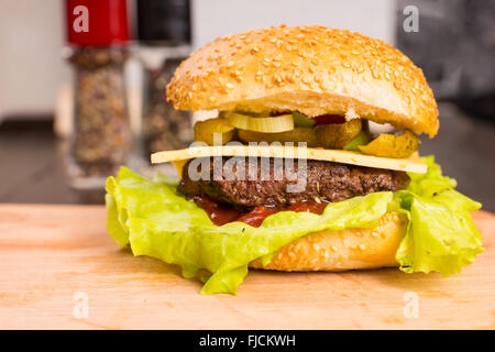 Close Up Portrait of hamburger grillé gastronomique avec du fromage frais et de nappages sur planche à découper en bois sur le comptoir de la cuisine Banque D'Images