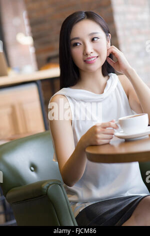 Jeune femme chinoise de boire du café au café Banque D'Images