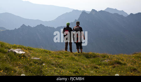 Les randonneurs de couple admiring view et prendre des photos de hautes montagnes Banque D'Images