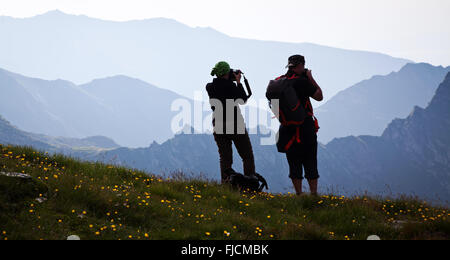 Les randonneurs de couple admiring view et prendre des photos de hautes montagnes Banque D'Images