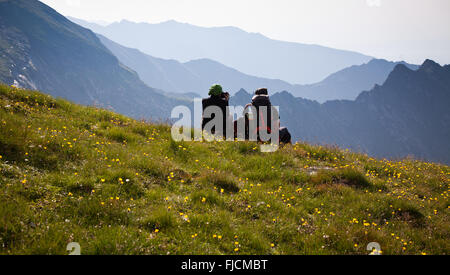 Les randonneurs de couple admiring view et prendre des photos de hautes montagnes Banque D'Images