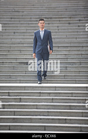 Portrait of a happy Asian businessman descendant des escaliers. L'homme d'affaires chinois la marche à l'extérieur. Banque D'Images