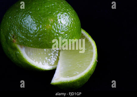 Une macro image d'un fruit lime kaffir Lime, peut-être (Citrus hystrix) avec un coin coupé. Banque D'Images