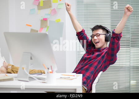 Jeune homme d'origine chinoise à écouter de la musique in office Banque D'Images