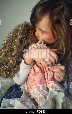 Triste et effrayé little girl hugging a doll Banque D'Images