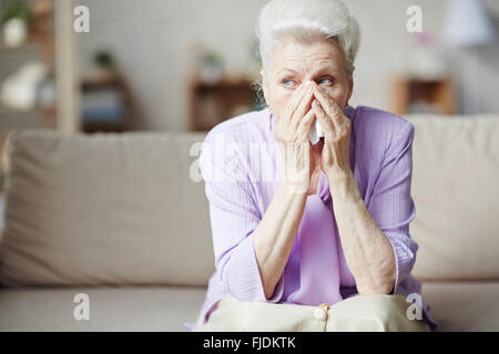 Sad senior woman sitting on sofa et pleurer Banque D'Images