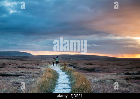 Deux marcheurs profiter d'un coucher de soleil spectaculaire en marchant sur le Pennine Way de Bleaklow à Kinder scout dans le Peak District. Englan Banque D'Images