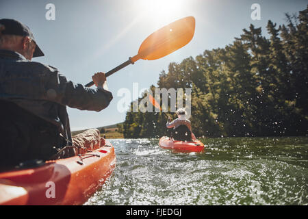 Piscine shot of senior man canoë dans le lac avec femme en arrière-plan sur une journée d'été. L'homme et la femme dans deux différents kayaks Banque D'Images