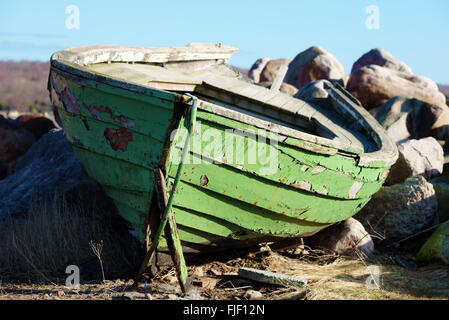 Une barque en bois noueux et sur terre. Le bateau est peint en vert. Les rochers de granit en arrière-plan. Banque D'Images