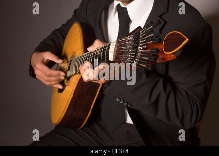 Gros plan d'un homme avec ses doigts sur les frettes d'une guitare portugaise Banque D'Images