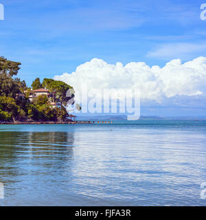 Pointe, les arbres, et le quai ou jetée sur un océan bleu et ciel nuageux. Bay Beach à Monte Argentario, Porto Santo Stefano, Toscane, Banque D'Images