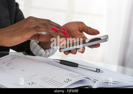 Femme travaillant avec un téléphone mobile au-dessus des documents d'entreprise Banque D'Images