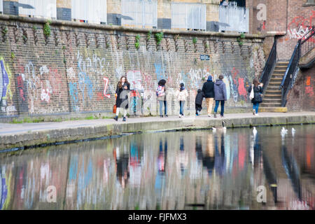 Promeneurs sur Regents Canal de halage, reflétée dans l'eau passant sur graffiti wall, Londres en février Banque D'Images